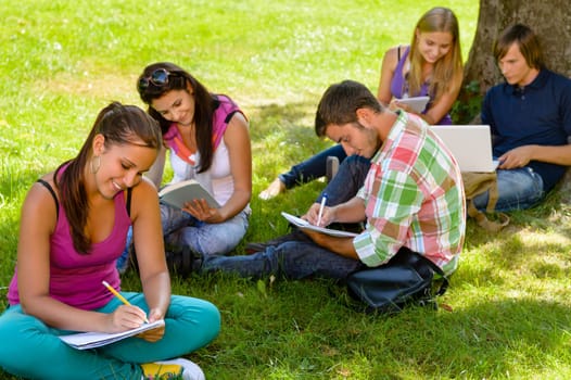 Students sitting in park studying reading writing teens campus schoolyard