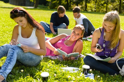 Teens studying in park reading book students happy campus research