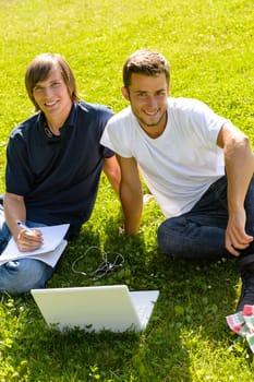 Teens sitting in park with laptop students happy studying campus