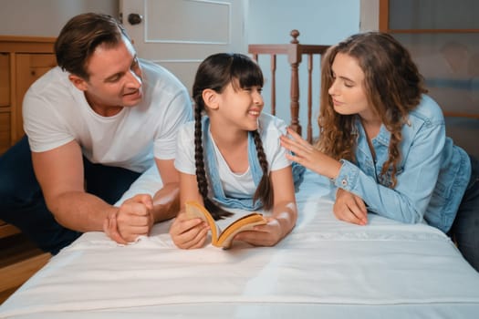 Bedtime story with childhood storytelling, mom and dad reading a fantasy book together to their little young girl in cozy and comfortable bedroom. Modern family happy time. Synchronos