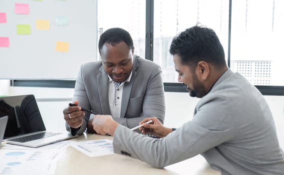 two business people talk project strategy at office meeting room. Businessman discuss project planning with colleague at modern workplace while having conversation and advice on financial report..