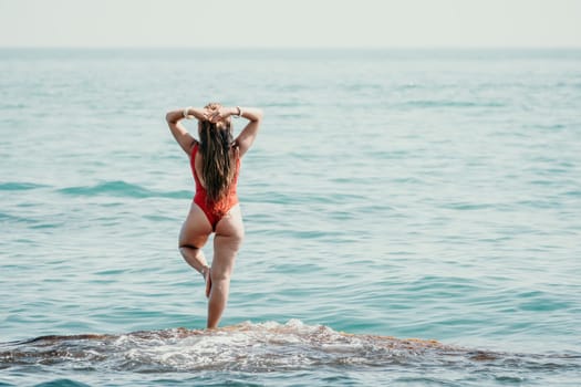 Woman sea yoga. Back view of free calm happy satisfied woman with long hair standing on top rock with yoga position against of sky by the sea. Healthy lifestyle outdoors in nature, fitness concept.