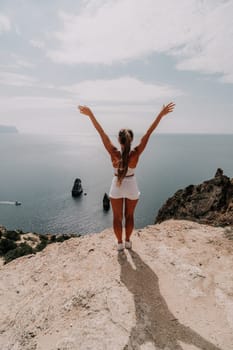 Woman travel sea. Happy tourist in hat enjoy taking picture outdoors for memories. Woman traveler posing on the beach at sea surrounded by volcanic mountains, sharing travel adventure journey