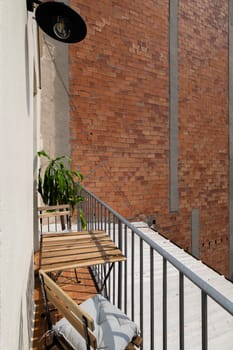 Small table with seats on open balcony near brick wall in Barcelona. Comfortable chillout on balcony in old residence house. Spain lifestyle tradition
