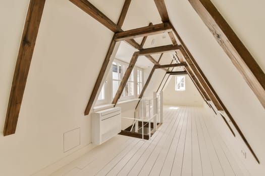 an attic room with white walls and wooden beams on the ceiling there is a small desk in front of the window