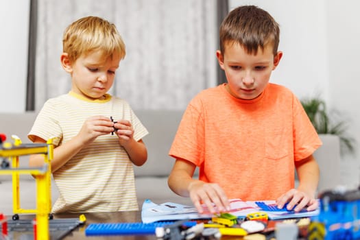 Two children playing and building with colorful plastic bricks at the table. Early learning and development.