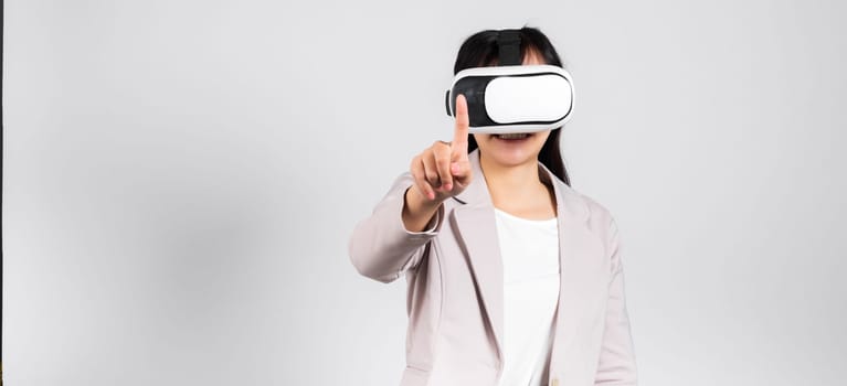 Smiling woman confidence wearing VR headset device touching air during virtual reality experience isolated white background, Asian happy portrait female playing video game studio shot, copy space