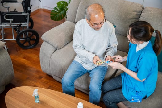 Woman nurse caregiver showing prescription drug to senior man at nursing home, healthcare support, Asian doctor with physician visit senior male patient consult medicine dosage at house in living room