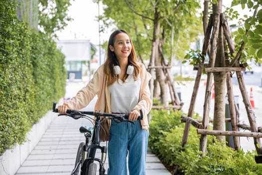 Lifestyle Asian young woman walking alongside with bicycle on summer in countryside outdoor, Happy female smiling walk down the street with her bike on city road, ECO environment, healthy travel