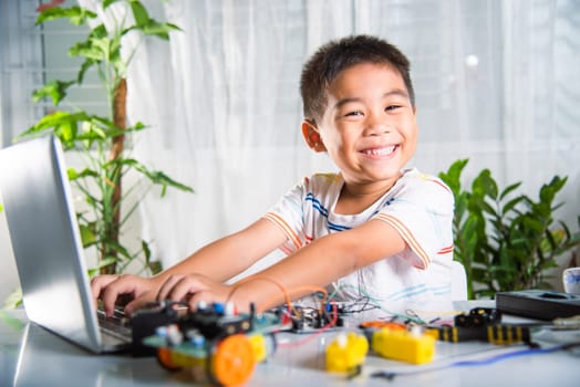 Asian kid boy learns coding and programming with laptop for Arduino robot car, Little child students typing code in computer online with car toy, STEAM education AI technology future course learning