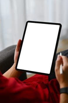 Close up shot creative male freelancer holding stylus pen using digital tablet on sofa.