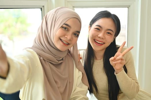 Cheerful female friends taking selfie with smartphone for post on blog or social media.