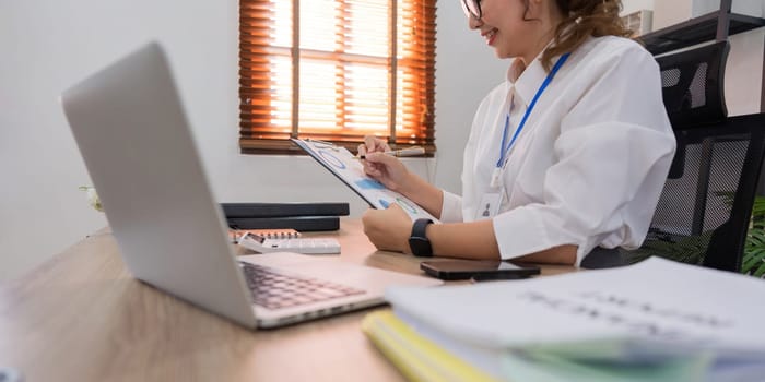 Asian businesswoman working on financial and accounting document on office desk.