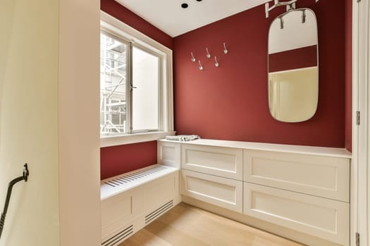 a bathroom with red walls and white cabinets on the wall, along with a large mirror over the bathtub