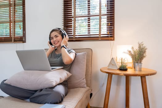 Asian beautiful woman smile at home in headphones. young woman listen music at home. Use technology, lifestyle concept.