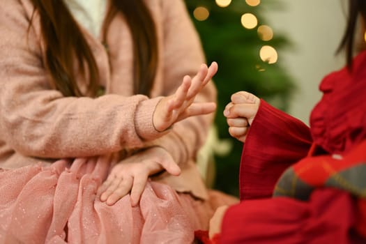 Two little girls playing rock paper scissors in living room during the Christmas holiday and New Year.