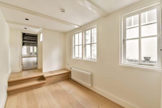 an empty room with white walls and wood flooring on the right, there is a window to the left