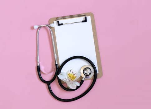 Stethoscope, white flower and empty blank for prescription on pastel pink background