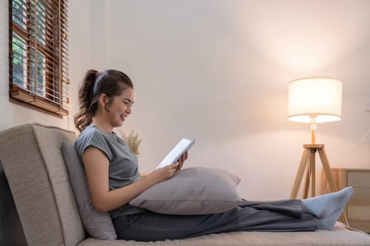 Happy young woman read book on sofa at home. Lifestyle freelance relax in living room. Lifestyle Concept.