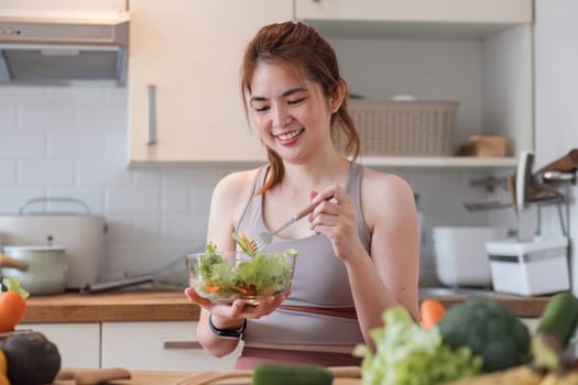 Young athletic woman is preparing a healthy organic vegetable salad in a modern kitchen at home..