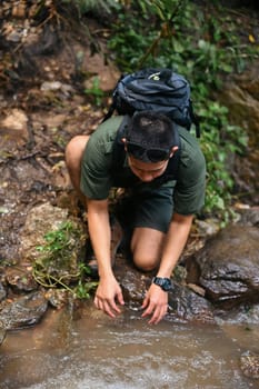 Man tourist hand touching clear water of mountain stream. Travel, adventure and active life concept.