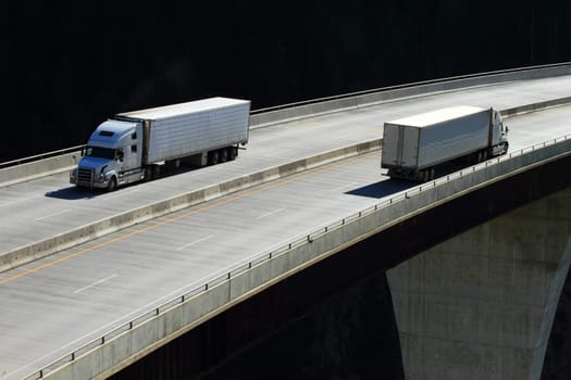 Semi-trailer trucks crossing a high level bridge in British Columbia