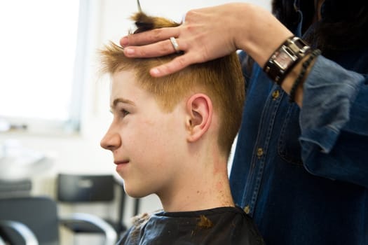 smiling young boy with red hair at the hairdresser