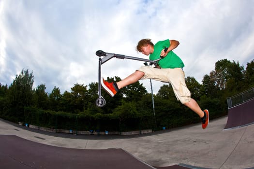 cute boy jumping in the air with his scooter