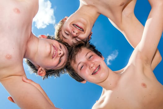 Low angle view of happy guys standing together in a circle against blue sky