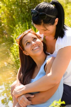 Mother holding her teen daughter in arms hugging smiling outdoors
