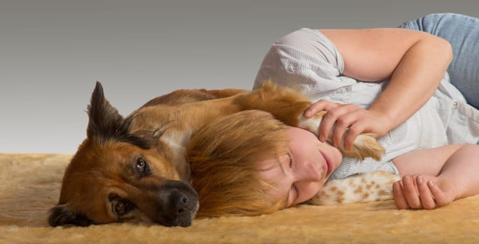 Woman lying on the floor enjoying a peaceful slumber with her head resting between the paws of her gentle protective dog