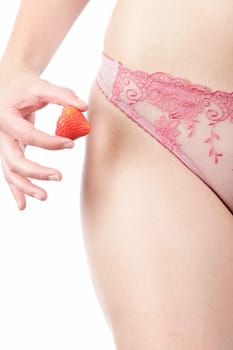 Close up of a woman's waist in underwear holding a fresh Strawberry in her right hand