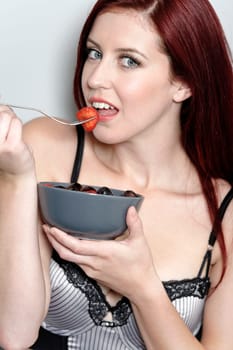 Beautiful young woman eating fresh fruit at home in her underwear