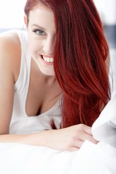 Young woman lying on her white bed at home relaxing