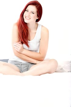 Beautiful young woman sitting on her bed at home