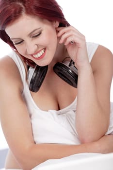 Attractive young woman listening to music at home on her bed