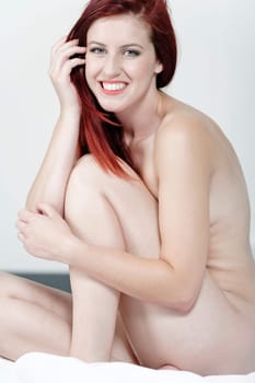 Beautiful young woman naked on her bed at home relaxing on the white covers
