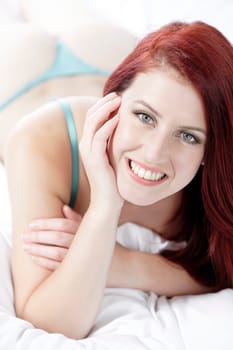 Beautiful young woman resting on her bed at home in her underwear