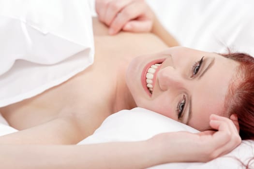 Attractive young woman holding a pillow on her bed at home