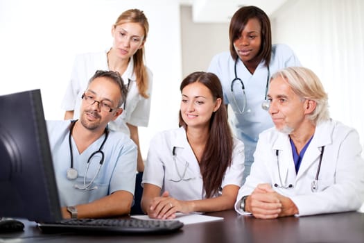 Friendly group of doctors at the hospital looking at a computer