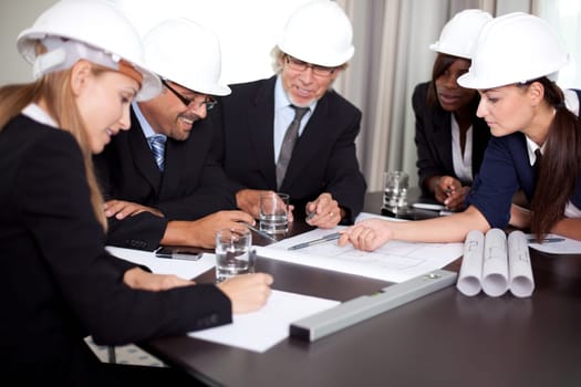 Happy successful engineers brainstorming on a new project with the blueprints