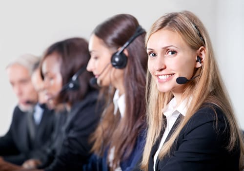 How can I help you? Closeup portrait of beautiful young female customer service representative with colleagues
