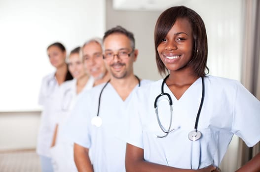 Multi-ethnic team of confident happy doctors standing in a row at the hospital