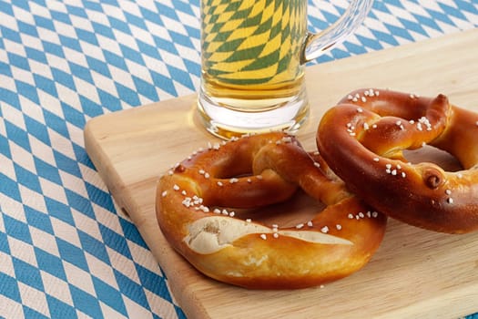 Two pretzels with a glass of beer on the Bavarian flag