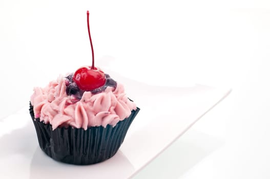Cherry cupcake close up on a white plate