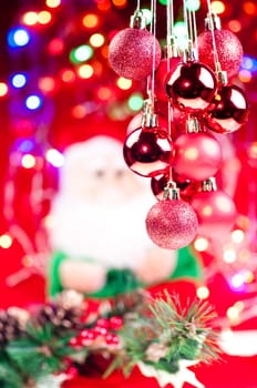 Red Christmas hanging baubles with santa , lights, and decorations at the background