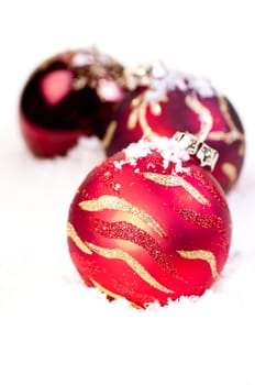 Three Christmas red baubles on snow as a white background