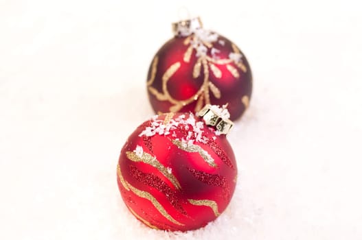 Two Christmas red baubles on snow as a white background