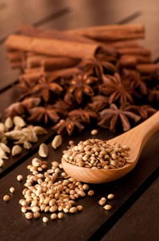 Spices on a wooden table and coriander on a spoon