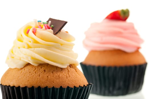 Vanilla cupcake with strawberry cupcake at the background over white
